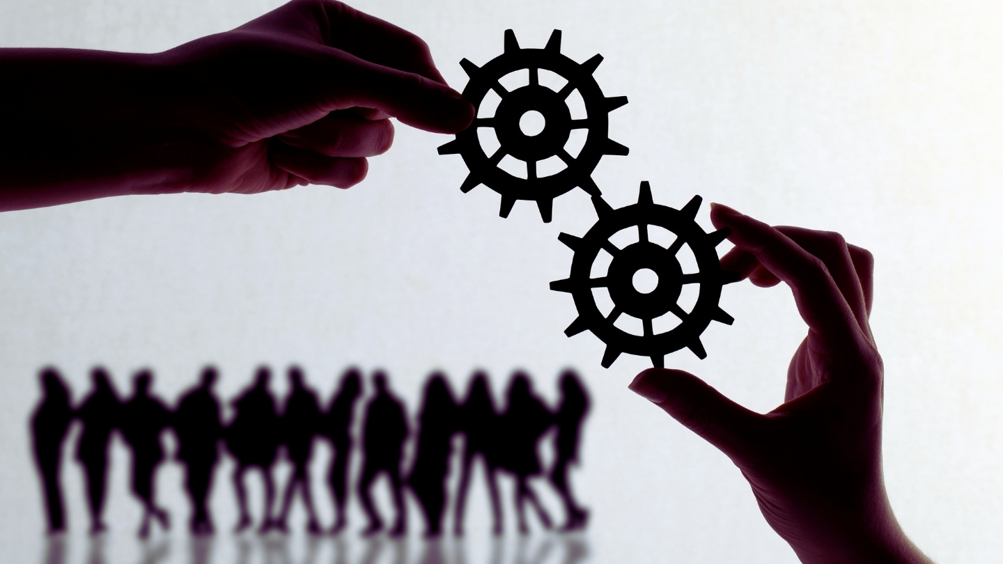 Koła zębate, w tle grupa ludzi.